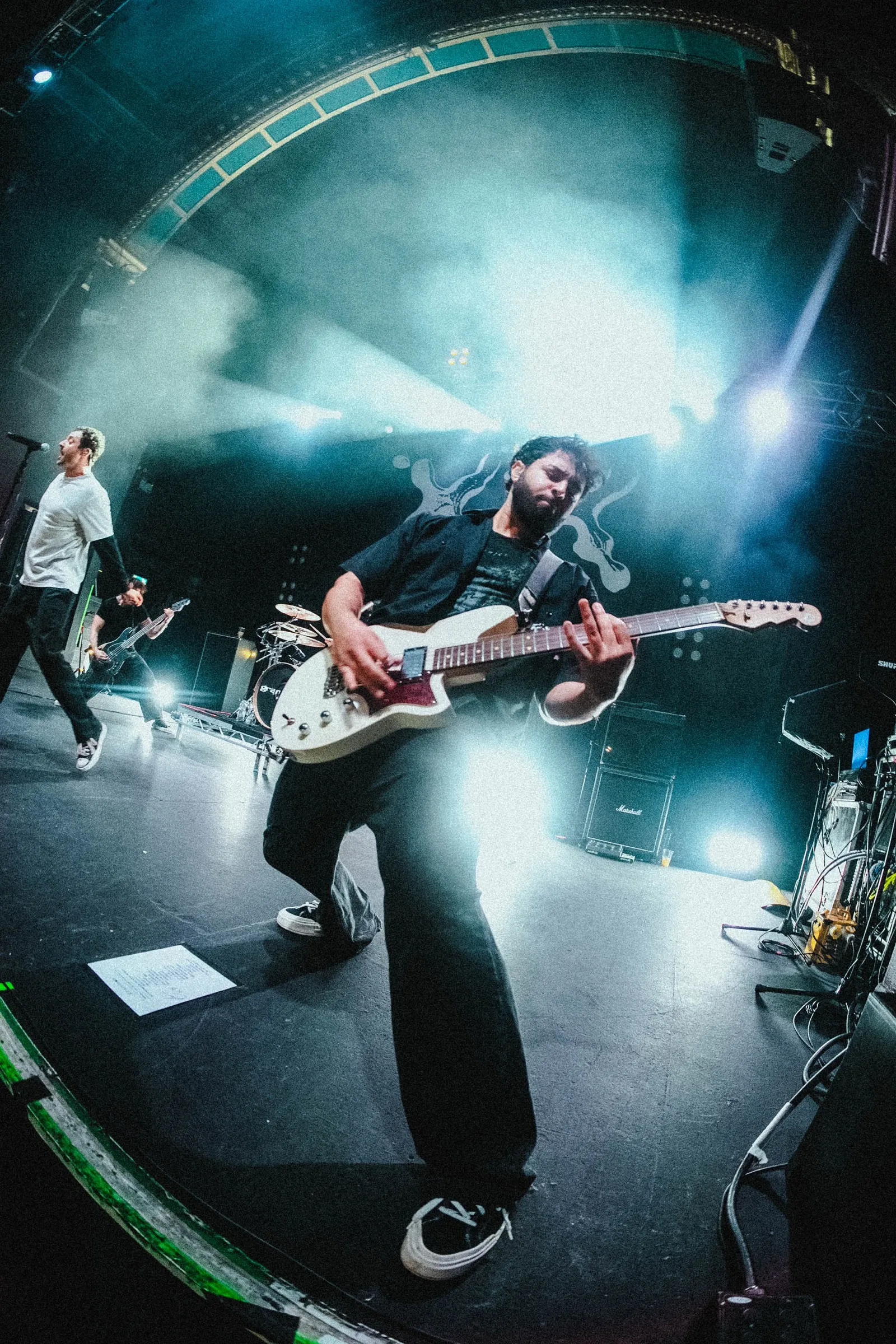 Amin Mortada playing guitar on a brightly lit stage