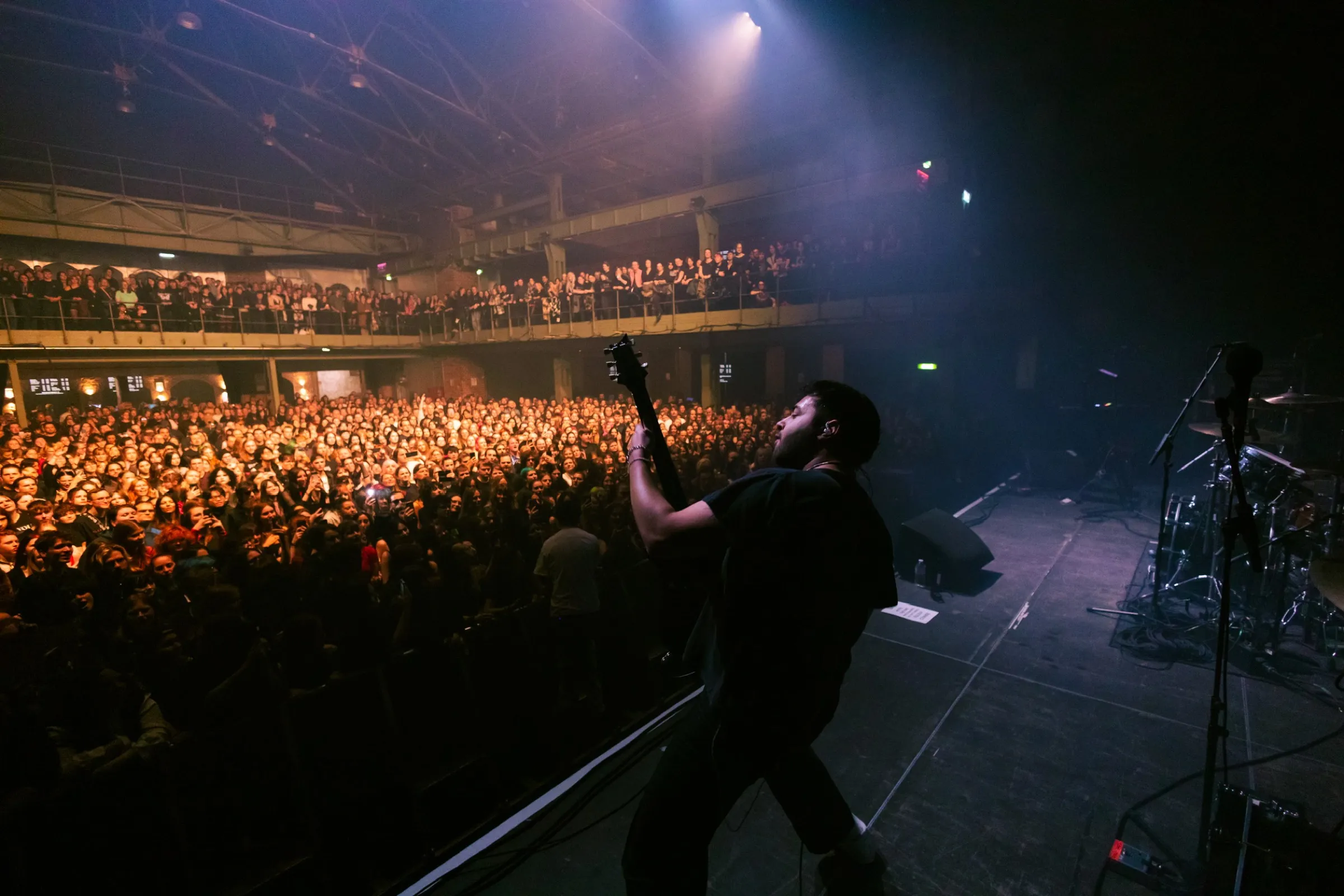 Amin Mortada holding guitar up to a packed venue crowd